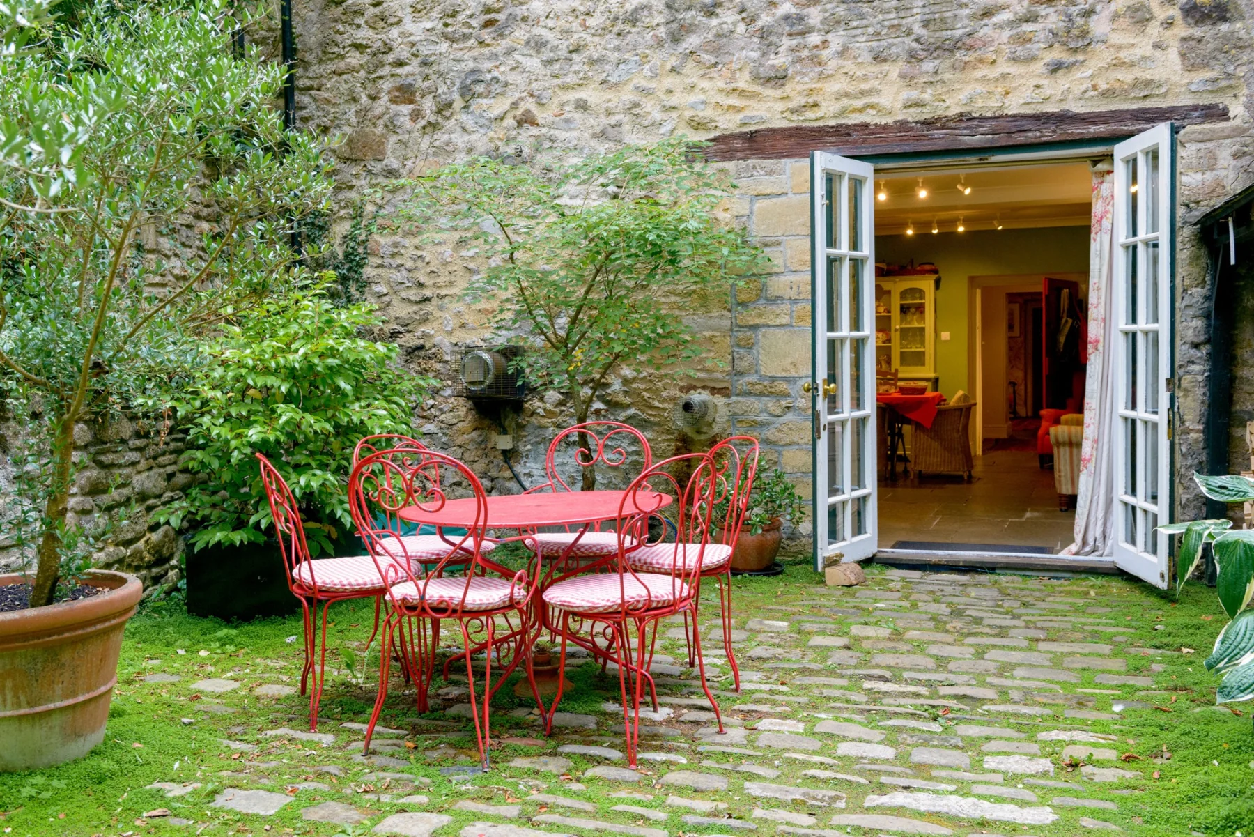 Red courtyard table and chairs beside the open kitchen doors