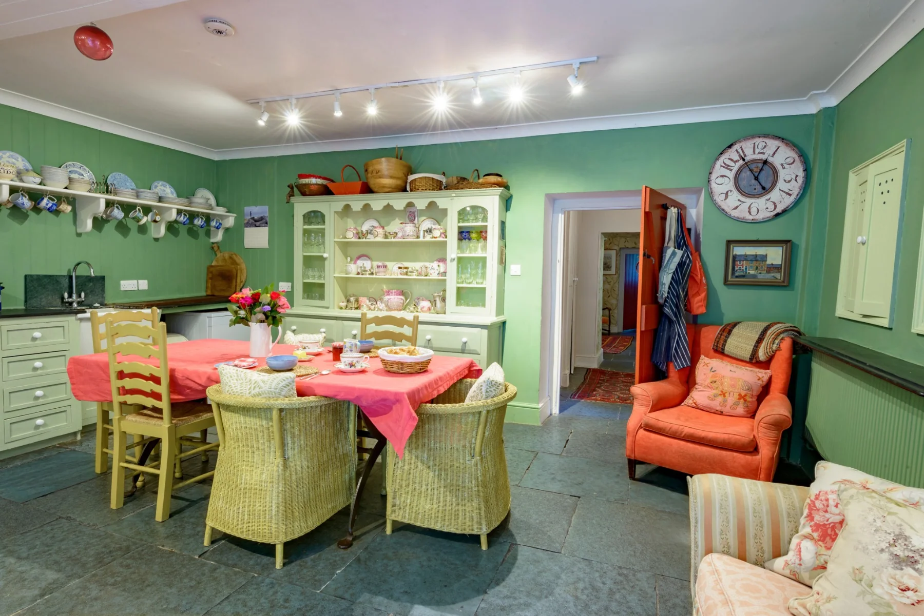 A wider view of the green kitchen with its chairs and dresser